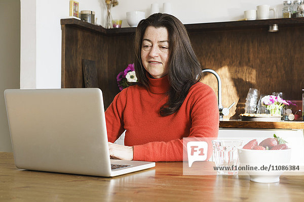 Close-up of mature woman using laptop on table at home