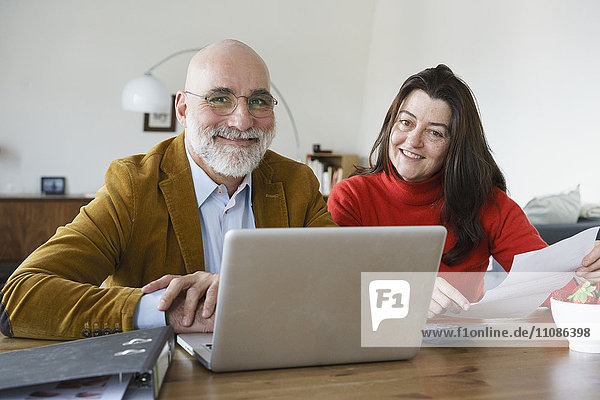 Portrait of mature couple using laptop at home