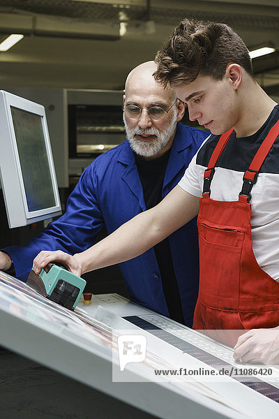 Mitarbeiter prüfen die Druckqualität mit Scanner an der Druckmaschine