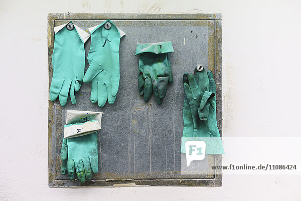 Grüne Handschuhe hängend an der Wand in der Fabrik