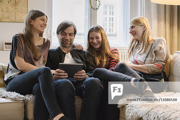 Glückliche Familie mit Vater mit digitalem Tablett im Wohnzimmer