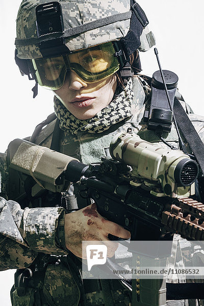 Soldatin mit Gewehr vor weißem Hintergrund