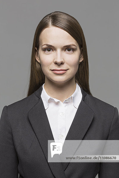 Porträt einer selbstbewussten Geschäftsfrau vor grauem Hintergrund