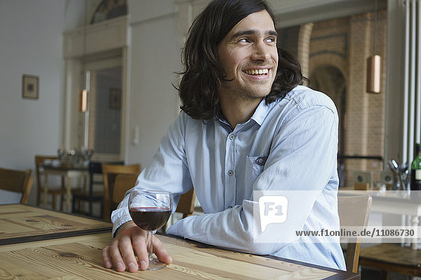 Happy man having wine while sitting at cafe