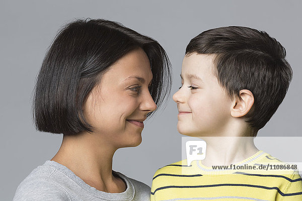 Smiling mother looking at son against gray background
