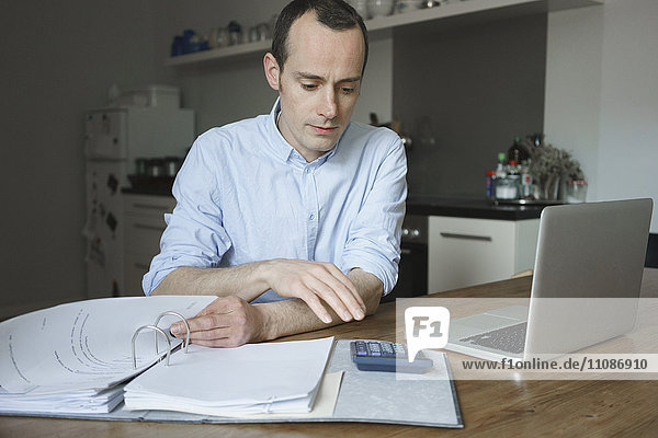 Serious man working with laptop and file at home