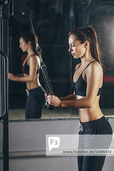 Young woman exercising with rope in gym
