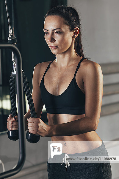 Concentrated young woman exercising with rope in gym