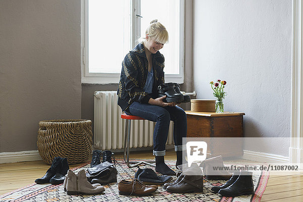 Happy woman holding shoes while sitting at home