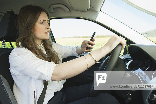 Businesswoman using mobile phone while driving car