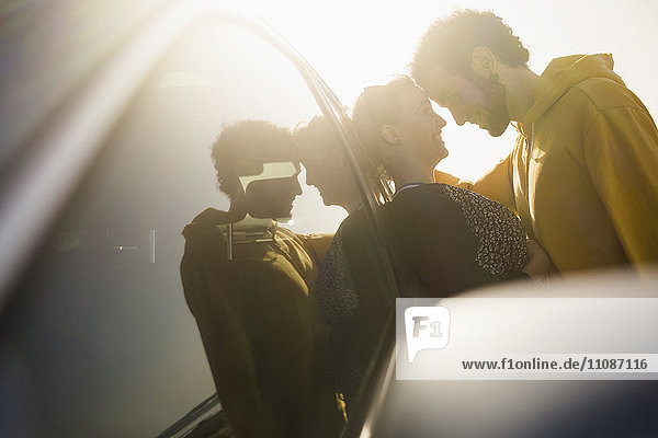 Seitenansicht eines romantischen Paares,  das sich auf das Auto stützt.