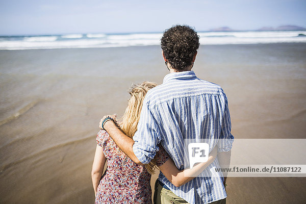 Rückansicht des liebenden Paares  das am Strand steht