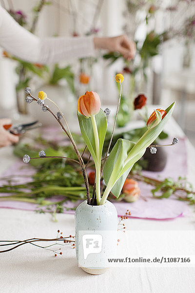 Blumenvase auf Tisch mit Frau im Hintergrund