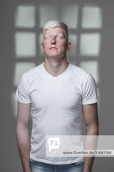 Albino-Mann mit geschlossenen Augen vor grauem Hintergrund