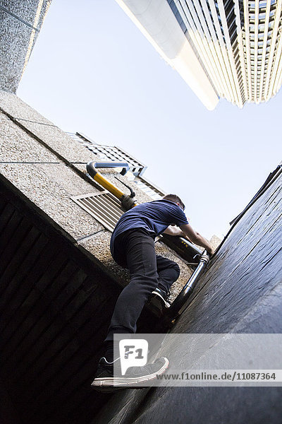 Spanien  Madrid  Mann klettert auf eine Mauer in der Stadt während einer Parkour-Session