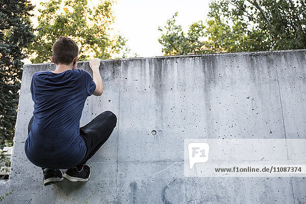 Spanien  Madrid  Mann beim Klettern an der Wand  während einer Parkour-Session
