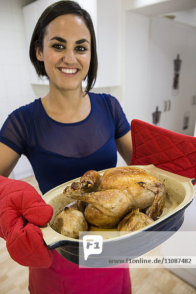 Smiling woman with a roast chicken