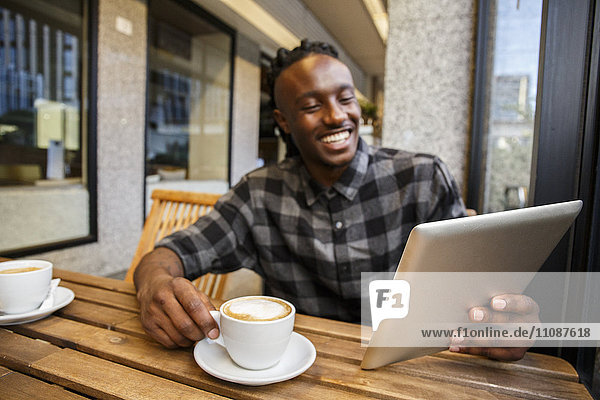 Young man sitting in cafe  using digital tablet
