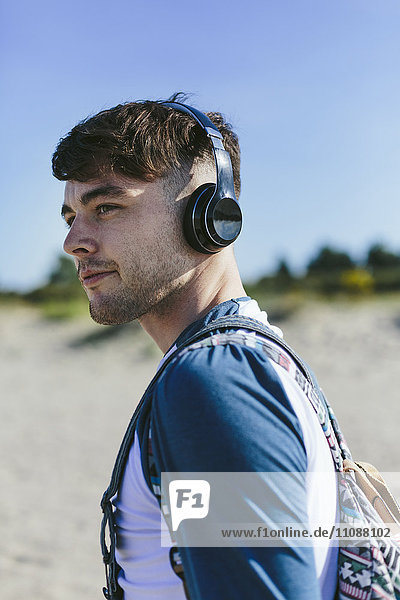 Young man with wireless headphones on the beach