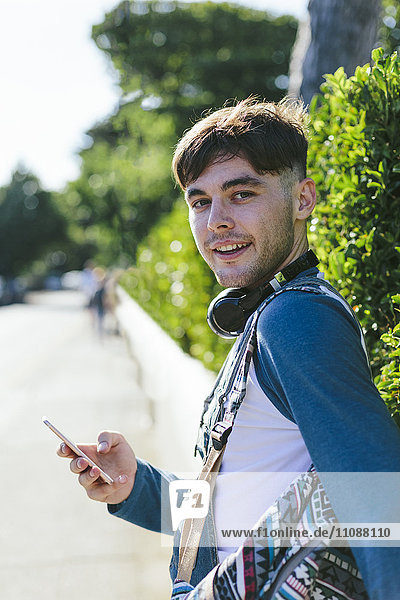 Portrait eines jungen Mannes mit Kopfhörer und Smartphone