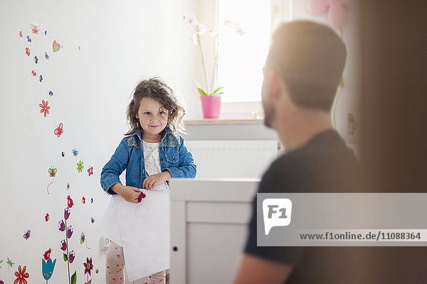 Mädchen mit Vater dekoriert Wand im Kinderzimmer