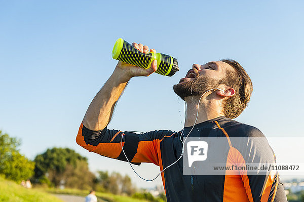 Sportler beim Trinken aus der Flasche im Park