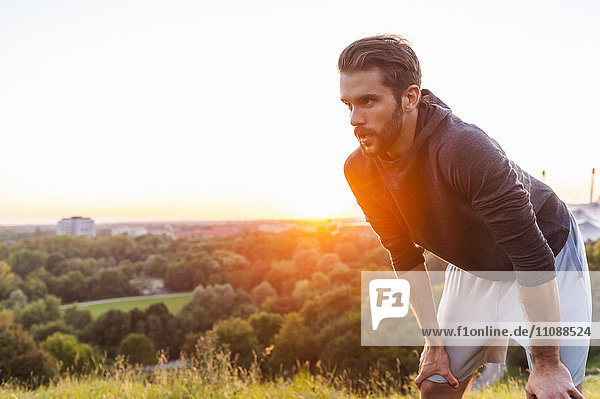 Athlet auf einem Hügel mit Pause bei Sonnenuntergang