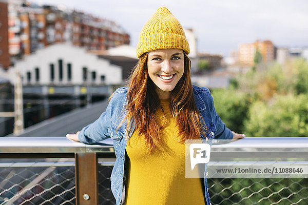 Porträt einer lächelnden jungen Frau mit gelber Mütze und gelbem Kleid