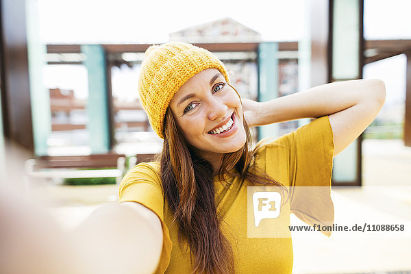 Porträt einer lächelnden jungen Frau in gelber Kleidung  die sich selbst trägt.