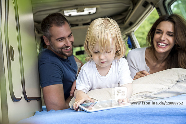 Glückliche Familie im Kleinbus mit Kleinkind mit Tablette