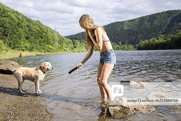 Young woman playing with her dog in a lake