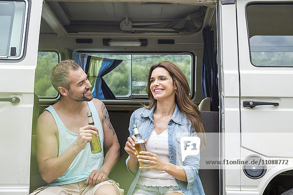 Lächelndes Paar mit Bierflaschen im Van