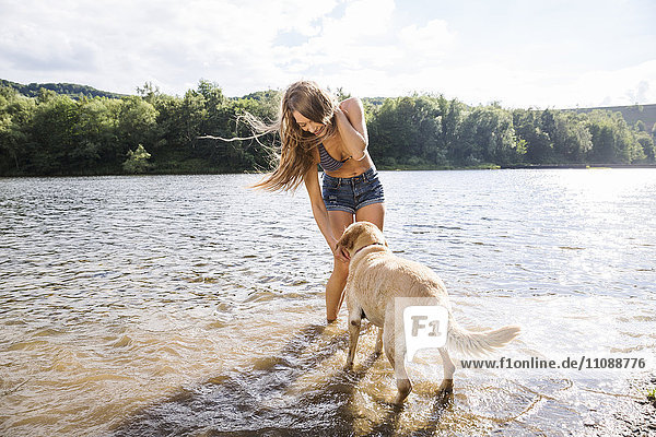 Junge Frau mit ihrem Hund im See