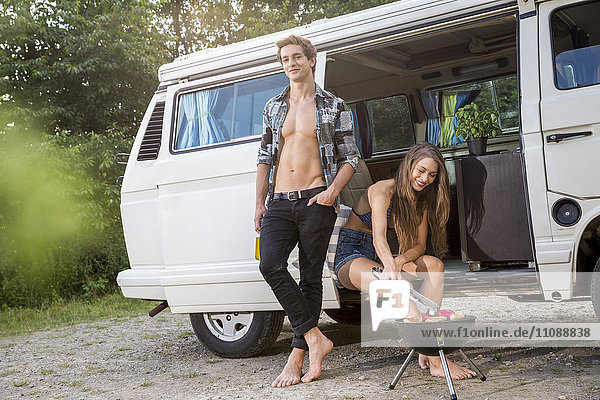 Young couple having a barbecue at a van