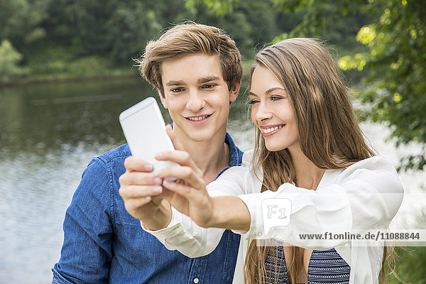 Junges Paar am Seeufer mit einem Selfie