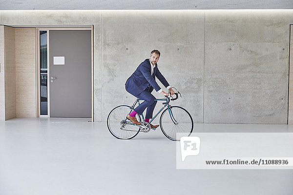 Businesssman riding bicycle in office building