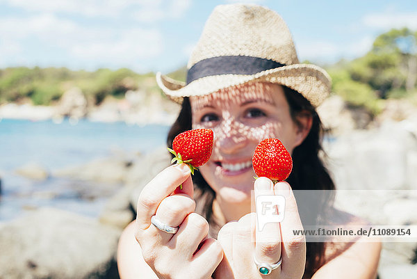 Frauenhände am Strand mit Erdbeeren