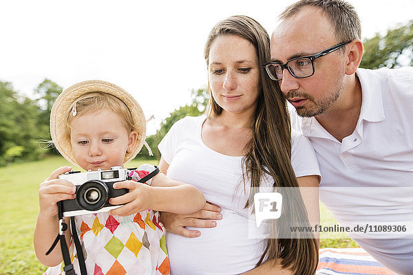 Glückliche Familie im Park  Tochter spielt mit der Kamera