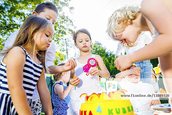 Children celebrating birthday party in the garden with friends and family