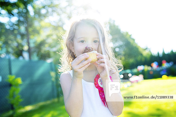 Little girl eating muffin in the garden