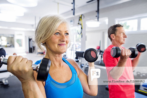 Mature woman and senior man working out in fitness gym