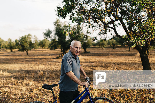 Senior man with bicycle on a field