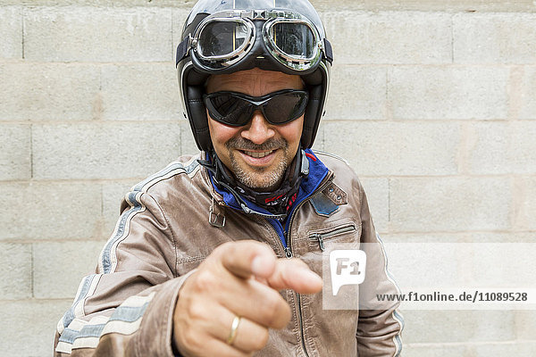Smiling biker wearing sunglasses and helmet pointing on viewer