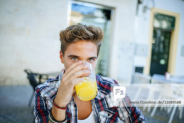 Junger Mann trinkt eine Orangenlimonade