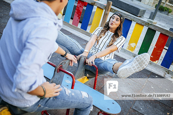 Junges Paar hat Spaß auf dem Rocker eines Spielplatzes
