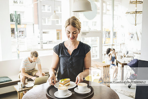Kellnerin im Café mit Kuchen und Kaffee