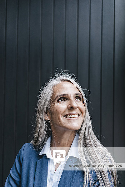 Porträt einer lächelnden Frau mit langen grauen Haaren nach oben schauend