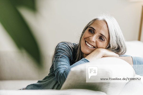 Lächelnde Frau auf der Couch zu Hause