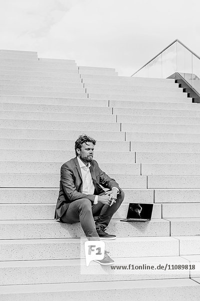 Geschäftsmann auf der Treppe sitzend mit Laptop
