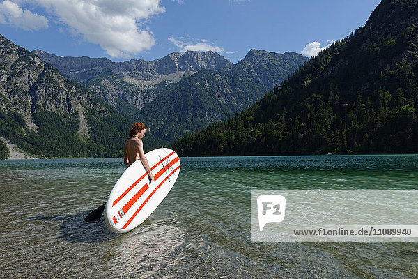 Austria  Tyrol Ammergau Alps  Plansee  Teenage Boy with paddleboard